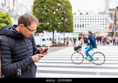 Tokio, Japan berühmten Shibuya Crossing und Fahrrad im Hintergrund auf Zebrastreifen in der Innenstadt von Stadt mit man touristische stehend an Richtungen auf Telefon Stockfoto