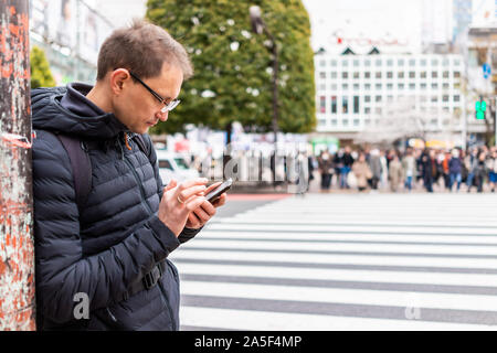 Tokio, Japan berühmten Shibuya Crossing in der Innenstadt von Stadt mit Nahaufnahme des Menschen touristische stehend an Richtungen auf dem Telefon suchen von Zebrastreifen Stockfoto