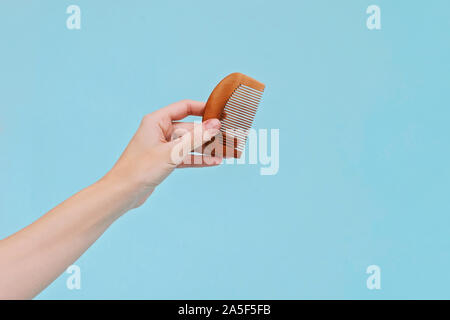 Holz- flachen Kamm Haarbürste in der Hand der Frau auf blauem Hintergrund. Null Abfall Konzept. Stockfoto