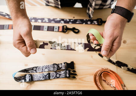 Überblick über die Hände des Handwerkers Holding einer der kreativen Halsband Werkstücke beim Wählen textile Muster Stockfoto