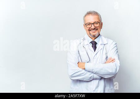 Fröhliche reife Arzt posing und lächelnd an Kamera, Gesundheitswesen und Medizin. Auf blauem Hintergrund isolieren. Stockfoto