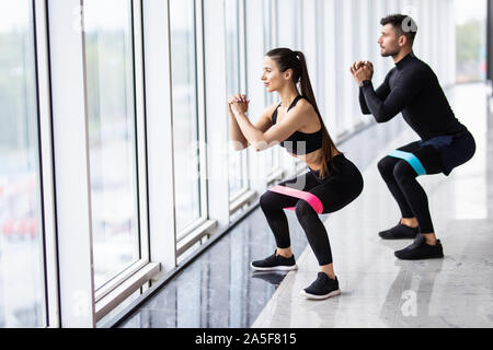 Attraktive Paar Training mit einem Widerstand Band In der Turnhalle als Teil der Fitness Bodybuilding Training Stockfoto