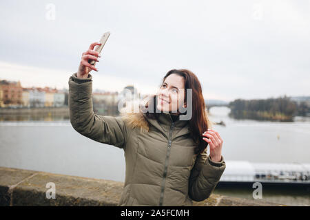 Glückliche junge Frau nimmt Selfie portrait auf der Karlsbrücke, Prag, Tschechische Republik. Ziemlich touristische machen lustige Fotos für Reisen Blog in Europa. Frau Stockfoto