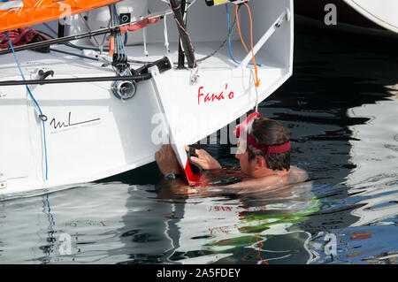 Sailor Inspektion seiner 650 Klasse Racing Yacht nach der ersten Etappe der Transatlantischen Minitransat Rennen Stockfoto