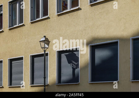 Straßenlaterne auf der Pole oder Straße Licht auf Gehweg mit ihrem Schatten werfen auf typische architektonische Fassade Stil in Europa mit ähnlichen Windows. Stockfoto