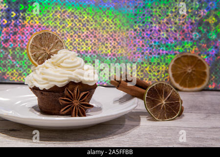 Weihnachten Muffins mit Mascarpone bereifen, getrocknet Zitrusfrüchte, Orange, Zitrone und Limette Dekoration, Zimtschnecken und Anis Sterne. Farbenfrohe backgroun Stockfoto