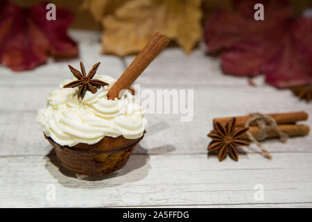 Pumpkin spice Cupcake mit Zimtstangen und Anis Dekoration. Herbst Spice hausgemachte Muffins mit Kürbis, Creme - Käse und Schlagsahne Puderzucker mit Yell Stockfoto