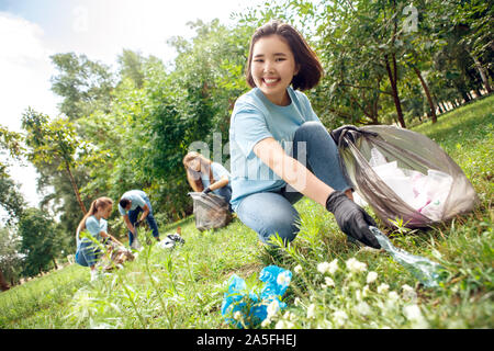 Freiwilligenarbeit. Die jugendlichen Freiwilligen im Freien asiatischen Mädchen Kommissionierung Wurf close-up lächelt Fröhlich Stockfoto