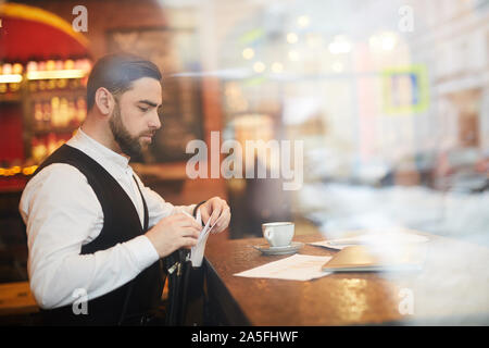 Seitenansicht Portrait von stattlichen Geschäftsmann im luxuriösen Restaurant arbeiten, geschossen von hinter Glas, Kopie Raum Stockfoto
