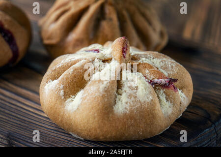 Brötchen Roggen Mehl liegen auf einem dunkel strukturierten Holz- Hintergrund. Hausgemachte Kuchen. Mexikanischen Tag der Toten Brot, Pan de Muerto. Stockfoto
