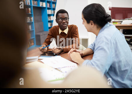 Multi-ethnischen Gruppe von Studenten zusammen in der Bibliothek, auf Afrikaner - Mann mit Brille, kopieren Raum konzentrieren Stockfoto