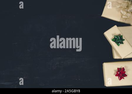 Oben Aufnahme einer schwarzen Holzfläche mit Geschenken auf Die Seite ideal zum Schreiben von Text Stockfoto