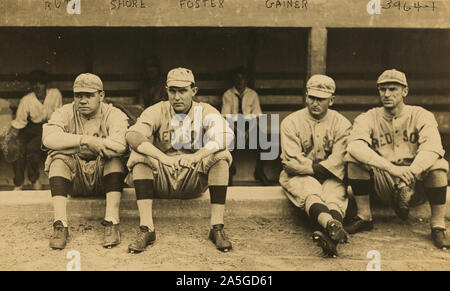 Foto zeigt George Herman "Babe" Ruth, Ernest G. 'Ernie' Ufer, George "Rube" fördern, und Dellos 'Del' Gainer, Vorderseite, das Tragen der Boston Red Sox Baseball Team Uniformen, sitzen auf einer niedrigen Mauer vor einem Unterstand. Stockfoto