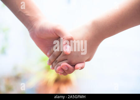 Die Hand des weiblichen Kind die Hand der älteren männlichen Schoß mit bokeh Hintergrund und horizontal. Konzept der Vatertag (16. Juni). Stockfoto