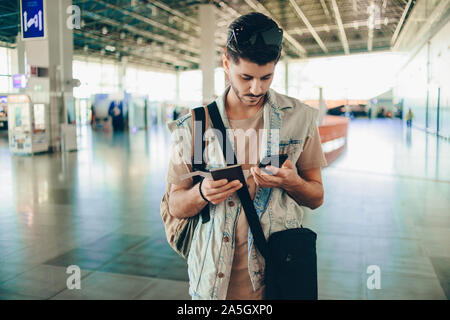 Hübscher junger Mann am internationalen Flughafen, nachdem Telefongespräch Anruf per Handy Stockfoto