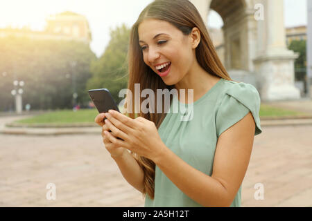 Überrascht euphorische fröhliche Frau ihr Smartphone ansehen in der Stadt. Stockfoto