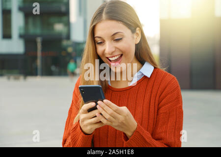 Überrascht euphorische fröhliche Frau ihr Smartphone ansehen in der Stadt. Stockfoto