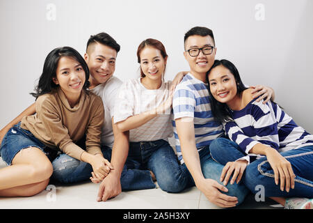 Group Portrait von glücklichen jungen asiatischen Menschen sitzen auf dem Boden und Kamera Stockfoto