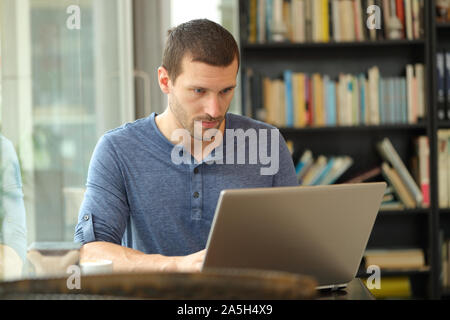 Ernster Mann mit einem Laptop die Eingabe von Daten in ein Café oder nach Hause sitzen Stockfoto