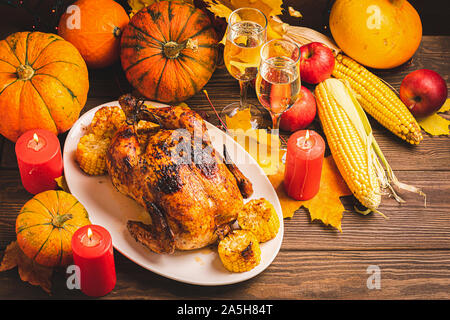 Festliche Truthahn oder Huhn gebacken von Thanksgiving auf einem weißen Teller zwei Gläser Champagner Wein Ernte von Gemüse der Saison: kürbis Mais Äpfel auf Stockfoto