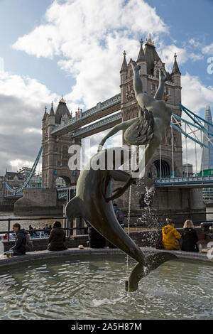 Der Junge mit einem Delphin Statue an der Themse in London, England, mit Tower Bridge im Hintergrund. Stockfoto