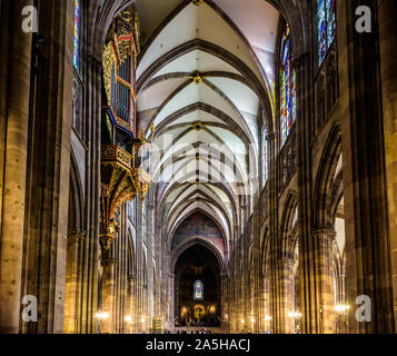 Das lange Kirchenschiff und Chor der Kathedrale Notre-Dame in Straßburg, Frankreich, beleuchtet durch Sonnenlicht mit der gefederten Orgel auf der linken Seite. Stockfoto