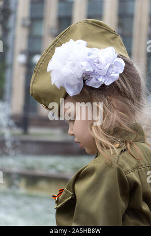 Kleine Mädchen in Uniform auf dem Hintergrund der Brunnen in der Nähe der Regierungsgebäude gekleidet. Weiße Schleife auf dem Kopf. Kinder des Krieges. Verteidiger der Stockfoto