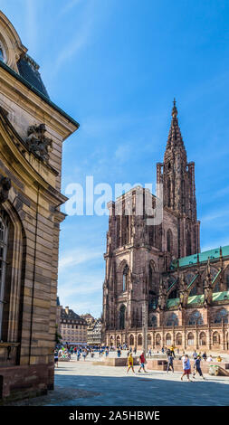 Der Turm der Kathedrale Notre-Dame in Straßburg, Frankreich, mit Menschen Flanieren auf der Place du Chateau und rohan Palast, in den Vordergrund. Stockfoto