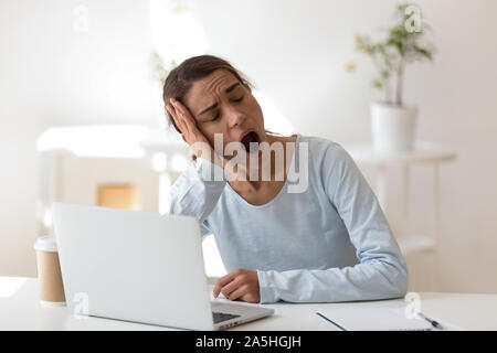 Müde junge Mixed Race Arbeiterin gähnen. Stockfoto