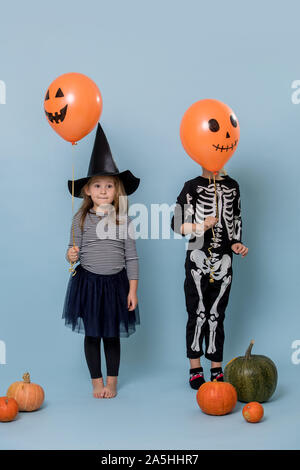 Zwei süße Kinder Hexe und Skelett Kostüme Holding orange halloween Ballons Stockfoto