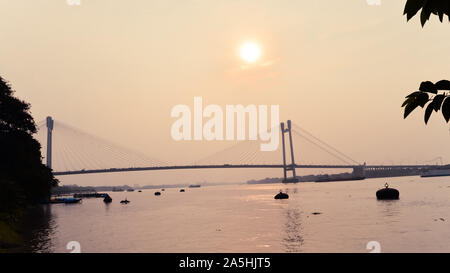 Sonnenuntergang über vidyasagar Setu (eine moderne Cantilever Spar Cable-Stayed Bridge) in ein Sommerabend auf dem Fluss Hooghly. Silhouette aus der Ferne. Wie Stockfoto