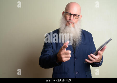 Wütend reife bärtige kahlen Geschäftsmann Holding digital Tablet und zeigen auf Kamera Stockfoto