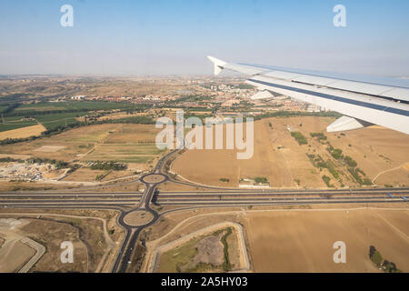 Blick durch das Fenster von Flugzeugen während des Fluges. Flugzeugflügel über blauen Himmel, Kreuzung und Stadtbild Hintergrund. Platz kopieren. Stockfoto