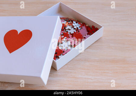 Box mit rotem Herz Puzzle auf weißem Holz- Hintergrund. Konzept für Liebe oder Nächstenliebe zu tun. Jedes Bisschen hilft Stockfoto
