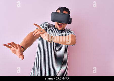 Junge Mann spielt Video Spiel virtual reality Brille tragen, mit Blick auf die virtuelle Simulation erstaunt und glücklich lächelnd Stockfoto