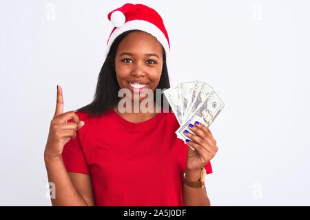 Junge afrikanische amerikanische Frau Mütze tragen und halten Bündel von Dollar Banknoten mit einer Idee oder Frage Zeigefinger mit Happ überrascht Stockfoto