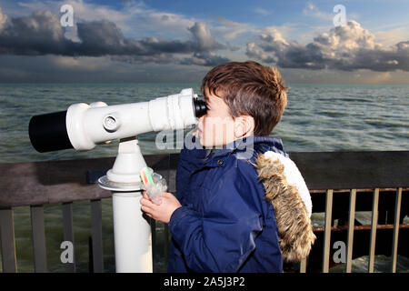 Junge Kind durch öffentliche Fernglas an der Hastings Pier in Tag suchen Stockfoto