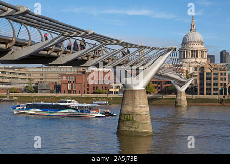 Menschen zu Fuß über die Millennium Bridge über die Themse in London, England, UK. Die Kuppel der St. Paul's Cathedral in der Ferne. Stockfoto