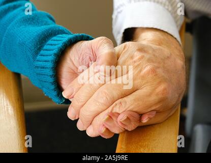 Alte Freunde (Mann und Frau) halten sich an den Händen in einem Pflegeheim Stockfoto