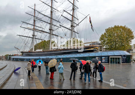 LONDON Greenwich, Cutty Sark Clipper und Touristen mit SONNENSCHIRMEN IM REGEN Stockfoto