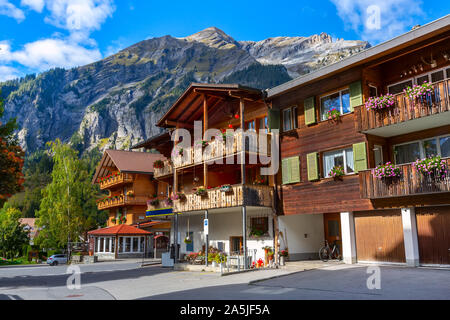 Kandersteg, Schweiz street view mit bunten Holzhäusern in Schweizer Dorf, Blumen auf dem Balkon und die Berge Panorama Stockfoto