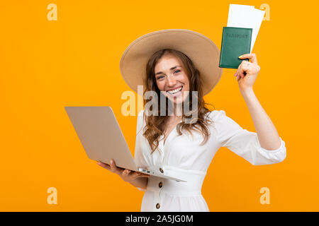 Moderne Mädchen kauft Tickets online, Portrait auf dem Hintergrund einer orange Wand Stockfoto