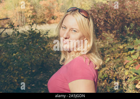 Porträt einer reifen Frau mit langen blonden Haaren im Herbst gefärbten Wald Stockfoto