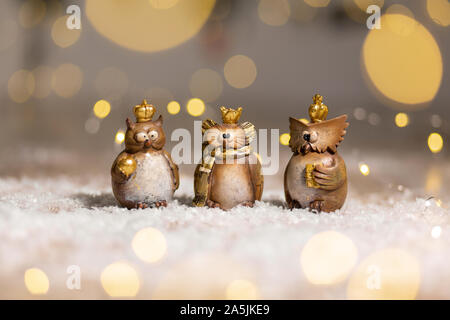 Satz von dekorativen Figuren Spielzeug Eule mit einer goldenen Krone auf dem Kopf. Festliches Dekor, warme Bokeh leuchtet. Stockfoto