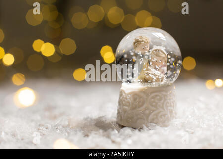 Die dekorativen Weihnachts-themed Figuren. Eine Glaskugel mit Schneeflocken, in dem zwei Männer an der Wiege suchen, ein Symbol für die Geburt Christi. Ch Stockfoto