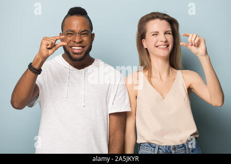 Lächelnd multirassischen Mann und Frau Lachen zeigen kleine Größe Messungen Stockfoto