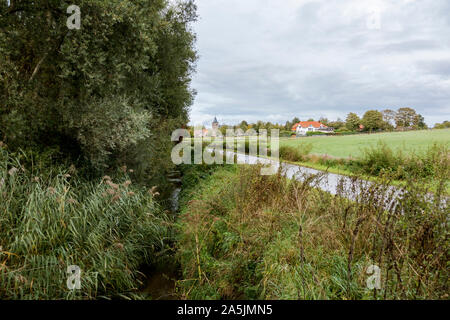 Kleine Straße durch deutsche Ackerland, mit grünem Erntegut, an der Grenze von den Niederlanden und Deutschland. Stockfoto