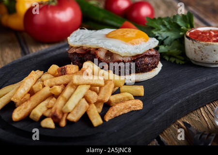 Rindersteak mit Ei und Salat aus grünen und Gemüse. Holz- Hintergrund, Tisch, feines Essen, Stockfoto