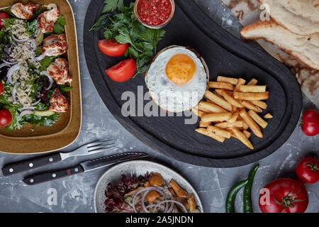 Rindersteak mit Ei und Salat aus grünen und Gemüse. Holz- Hintergrund, Tisch, feines Essen, Stockfoto