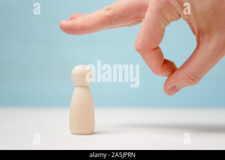 Männliche Hand geben ein noogie zu Holzfigur auf blauem Hintergrund. Konzept der Kick out. Stockfoto